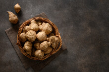 Raw Jerusalem Artichoke Root, Sunchokes In Wooden Wicker Basket And On Brown Background. View From Above. Copy Space.
