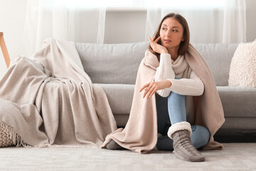 Poster - Young woman with warm plaid sitting on floor at home