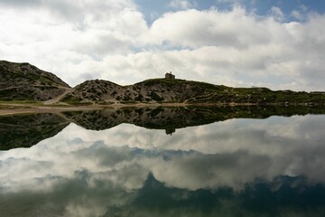 Sticker - Green valley and Lake Olbe in mountainous environment under dense clouds reflected in water, Italy