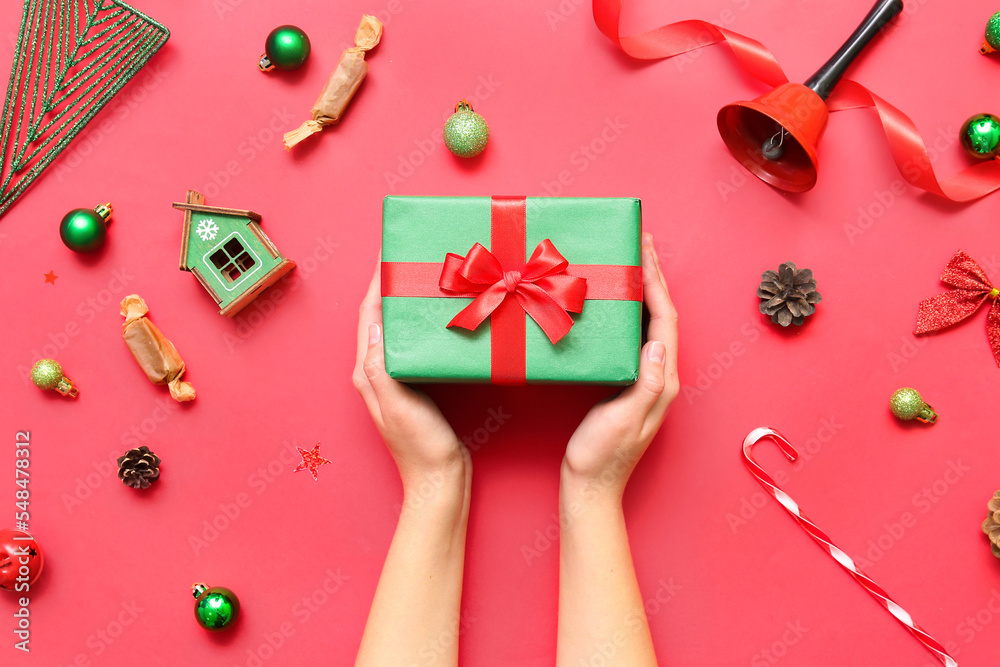 Woman with gift and Christmas decor on red background