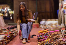 Gril Selecting From Two Pairs Of Sandals In Street Shop