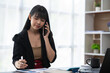 © crizzystudio - Asian businesswoman in formal suit in office happy and cheerful during using smartphone and working
