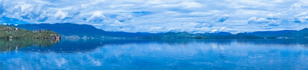 Poster - Panoramic view of the sea with land on the side under cloudy beautiful sky