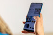 © Jelena - Female hand holding phone. Teen girl customer shopper using online mobile shopping app choosing buying  with mobile payments on cell tech, close up