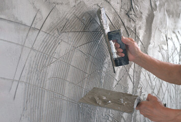 worker hands plaster over scratched new wall. plastering with scratch marks on first layers wall surface to helps second coat of plaster to adhere scratch coat create a bond between the two layers