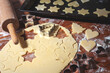 Weihnachtsbäckerei - aus hellem Teig werden auf einem Holztisch weihnachtliche Motive für Weihnachtsplätzchen ausgestochen