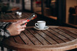 © Svitlana Ozirna - Women's hands with red manicures holding a cell phone at a table in a cafe with a cup of coffee