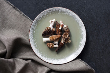 Morel mushrooms on a plate on black background