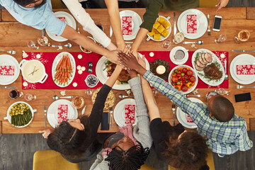 Hands, unity and Christmas with a table setting for dinner or a celebration even with friends from above. Food, together and motivation with a group of people bonding during a meal in the holidays