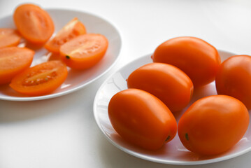 Wall Mural - Yellow ripe tomatoes on a plate on a white background. Tomatoes close-up.