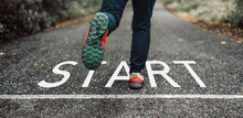 New Year 2023 Or Start Straight Concept.Word Start Written On The Asphalt. Start Concept. Low Section Of Woman Steps Into Start Line For Moving Forward To New Challenge. Cropped Image. Side View