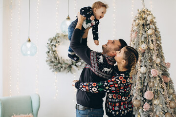 Portrait of happy family of father mother and little curly son celebrating Christmas together at home. New Year`s Eve concept.