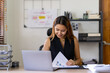 © crizzystudio - Portrait of an Asian businesswoman thinking View financial statements and make marketing plans, review documents, calculate numbers and record information in a notebook.
