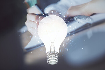 Poster - Drawing bulb over woman's hands taking notes background. Concept of idea. Double exposure