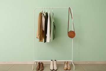 Wall Mural - Rack with stylish clothes, shoes and bag near green wall