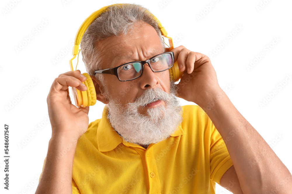 Confused senior man in headphones on white background, closeup