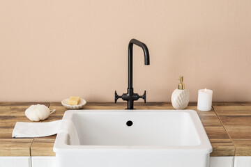 Wall Mural - Sink with bath accessories and burning candle on table near beige wall