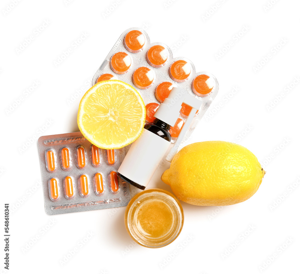 Spray for sore throat, pills, honey and lemons on white background