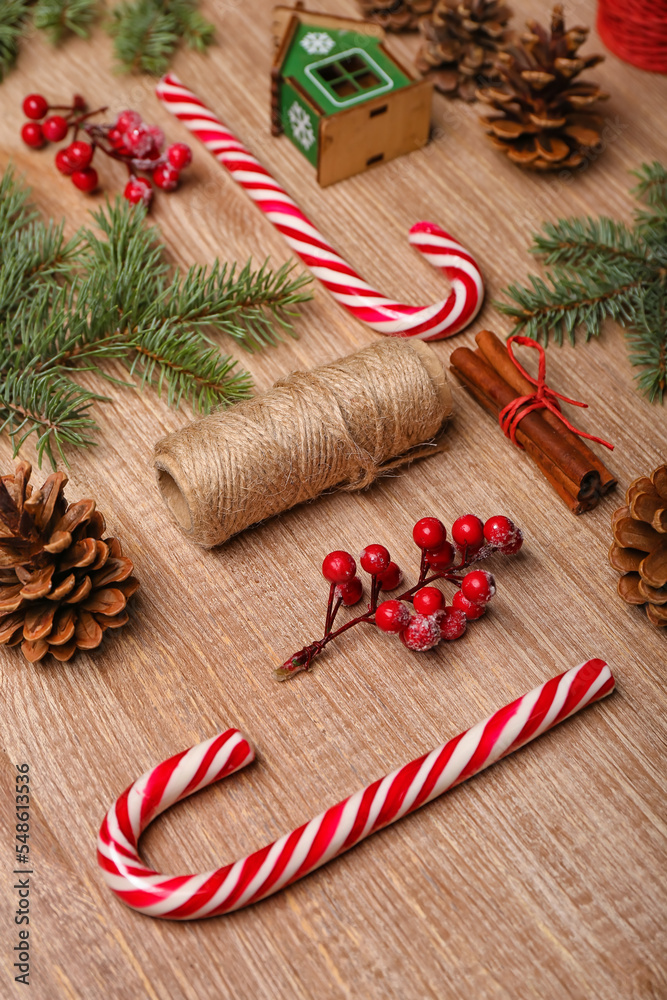 Composition with sweet candy canes, fir branches and cones on wooden background