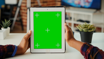 Poster - office employee vertically holding wireless device with greenscreen display, looking at chroma key t