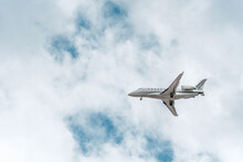 Small Commercial Passenger Jet Airplane In Mid Flight Against Cloudy Sky
