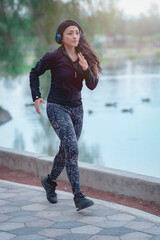 Wall Mural - Woman running on the path of a park. Healthy lifestyle concept. Athletic sports exercises for athletic people.