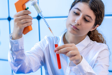 Sticker - filling a chemical test tube with a dispenser in a chemical laboratory a young woman on doing a scientific experiment