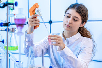 Sticker - filling a chemical test tube with a dispenser in a chemical laboratory a young woman on doing a scientific experiment