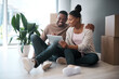 © T Hover/peopleimages.com - African couple, real estate and tablet for new house interior shopping, property or relax on floor with boxes. Realtor, happy online communication and homeowners moving or packing apartment together