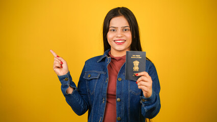 Young woman holding Indian passport, isolated over colour background, Beautiful girl holding visa pointing finger aside, towards copy space