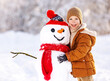 © JenkoAtaman - Happy child cute little boy in warm clothes with snowman in snowy winter park