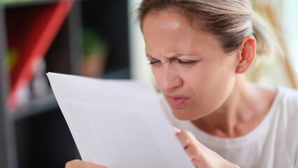 Concentrated female read papers, squinting to see more clearly