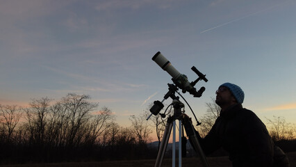 Wall Mural - silhouette of a man, telescope and countryside under evening skies.