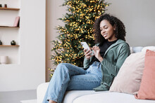 Young Woman Using Smartphone At Home During Christmas Holiday, Student Girl Texting On Mobile Phone Indoors, Connection, Online Shopping, Winter Lifestyle Concept