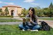asian Korean college student sitting crossed legged on lawn and reading book with concentration at school university in California usa near Memorial Auditorium Fountain