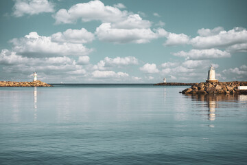 Two lighthouses facing each other in the port with clear sky and clouds. Clouds over the pier and lighthouses