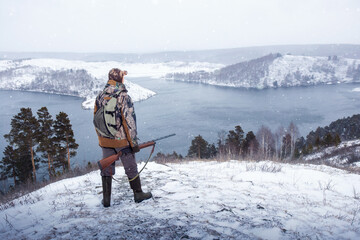 Wall Mural - Hunter with rifle during a winter hunt. Male hobby, activity lifestyle concept.