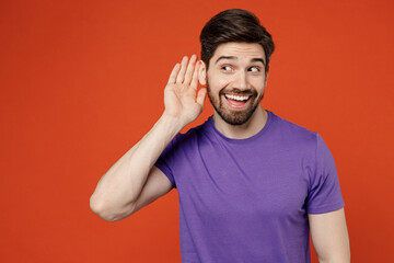 Poster - Young curious nosy brunet caucasian man 30s wear casual basic purple t-shirt try to hear you overhear listening intently isolated on plain orange background studio portrait. People lifestyle concept.