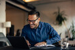 © bnenin - Smiling man searching something online, using a laptop.