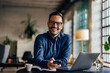 © bnenin - Smiling businessman looking at the camera, holding a phone, working from the office.