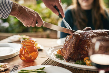 Wall Mural - Food, hands and turkey with family at a table in celebration of thanksgiving, tradition and lunch meal on a patio. Chicken, hand and man carving meat to share with friends at christmas party outdoor