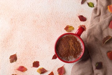 Wall Mural - Cup of hot drink, leaves and soft knitted fabric on beige textured table, flat lay with space for text. Cozy autumn atmosphere