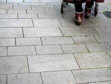 Füße Und Beine Von Alter Frau Mit Roten-beigen Stiefeln Scheibt Rollator über Grauen Steinfußboden In Stadt Am Morgen Im Winter