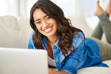 Woman, laptop and relax with smile on sofa for studying, streaming or freelance designer in remote work at home. Portrait of happy female freelancer or student smiling in comfort on living room couch