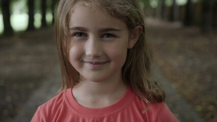 portrait smiling little girl looking at camera. laughs happily child at outdoors. inquisitive little