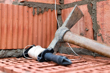  Construction tool for laying bricks and blocks. Bricklayer's tools - hammer, spatula, trowel, gloves. Hand tools on the background of brickwork.