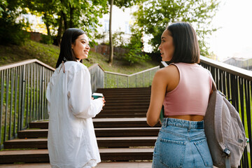 Wall Mural - Back view of two young beautiful smiling happy asian girls