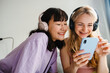 © Drobot Dean - Young beautiful smiling happy girls in wireless headphones watching video