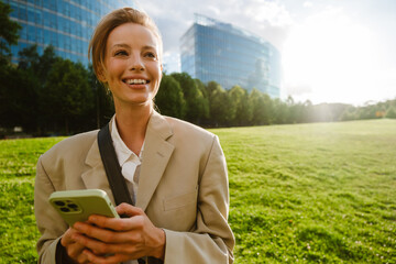 Wall Mural - Young beautiful smiling business woman holding phone and looking aside