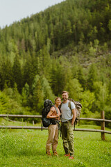 Wall Mural - White young couple with backpacks hiking in green forest